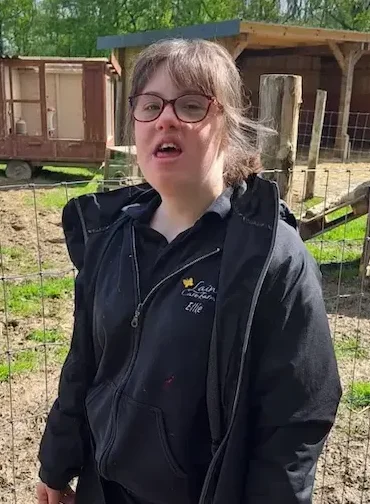 Young woman in outdoor gear standing in front of a farm enclosure at Lainey’s Care Farm.