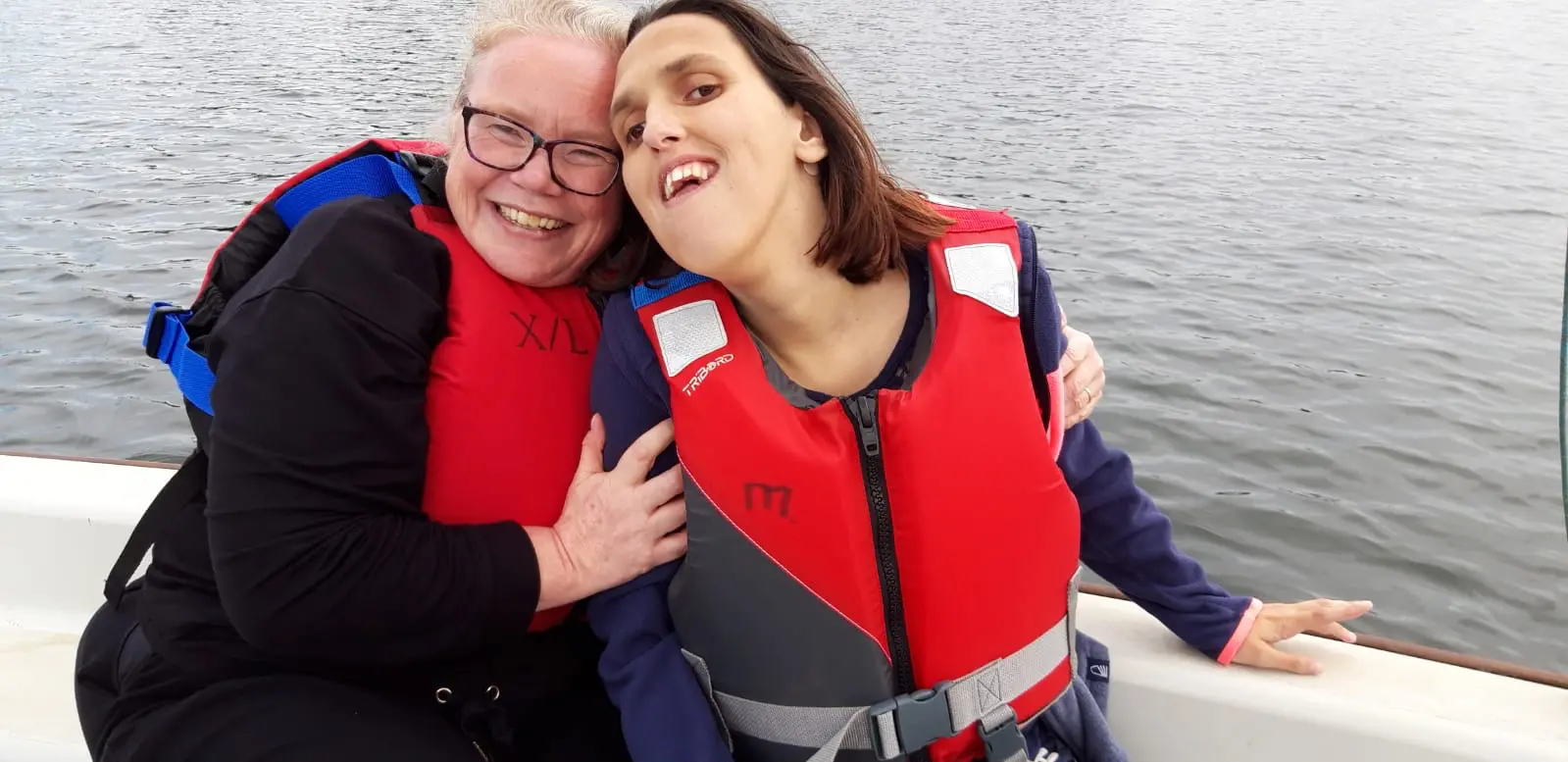 A care assistant and a client, enjoying a day trip out on the water in Kent, receiving compassionate, 24/7, complex care from Continuity of Care Services.