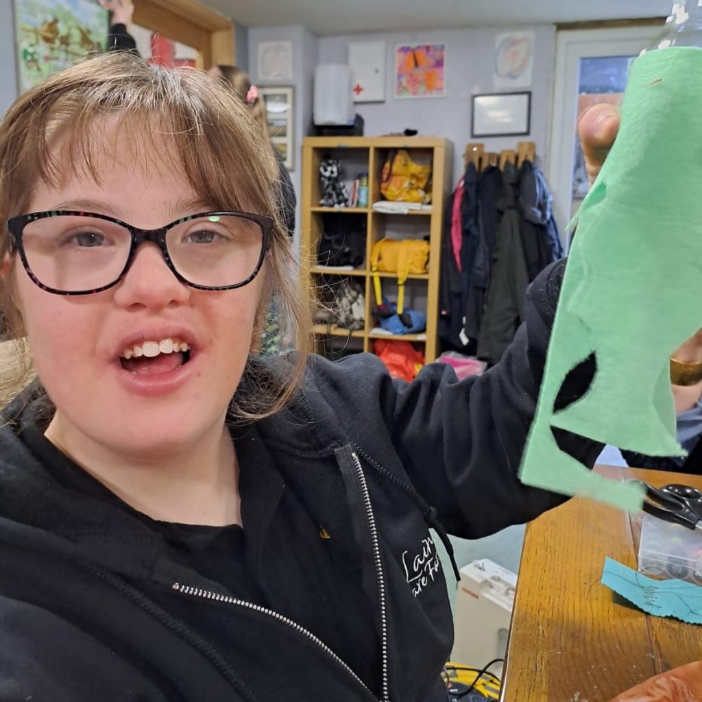 Personalised domiciliary care—crafting and companionship at home in Maidstone & Kent A smiling young adult receiving one-to-one support from a caregiver as they enjoy a felt-craft activity in a session at Laineys Care Farm