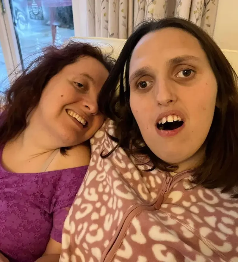 Night care sleepover, personalised overnight support and companionship in Maidstone & Kent Two women smiling together on a sofa during a cosy sleepover, supported by their care team during an overnight stay