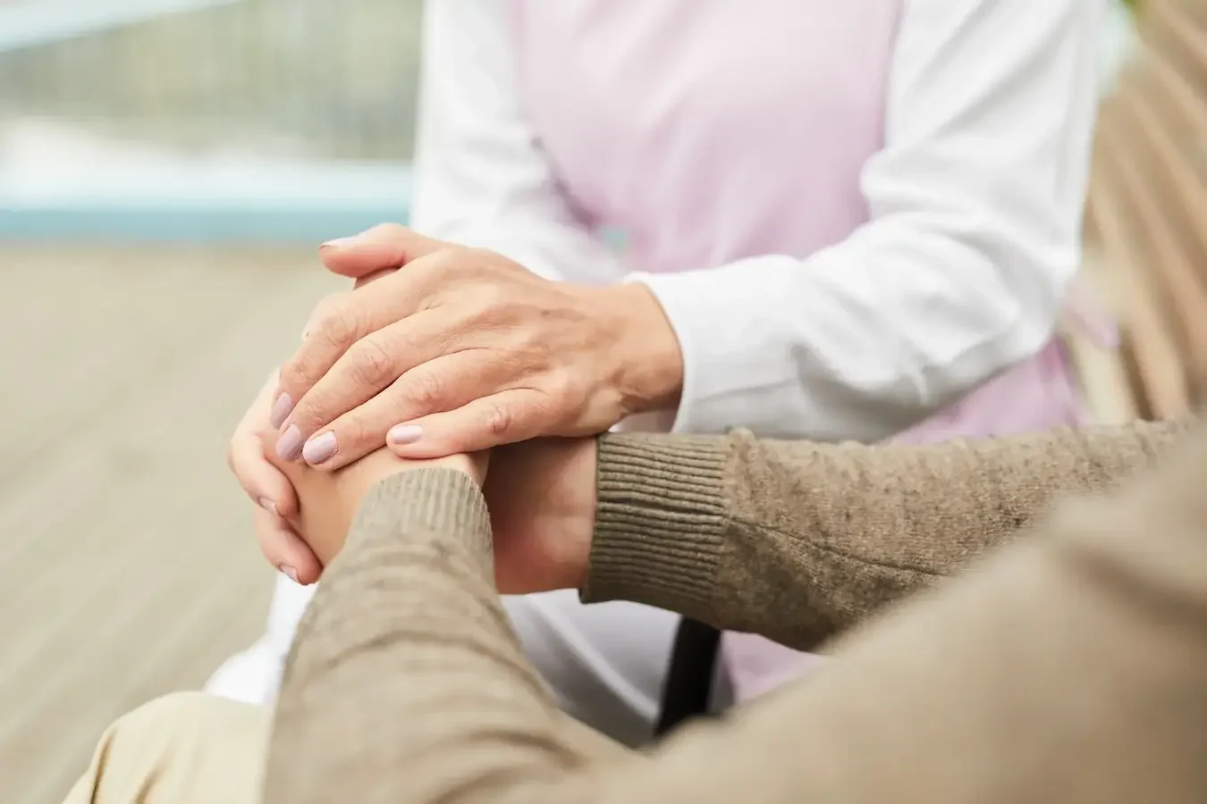 Care worker gently holding an older person's hand during a compassionate conversation