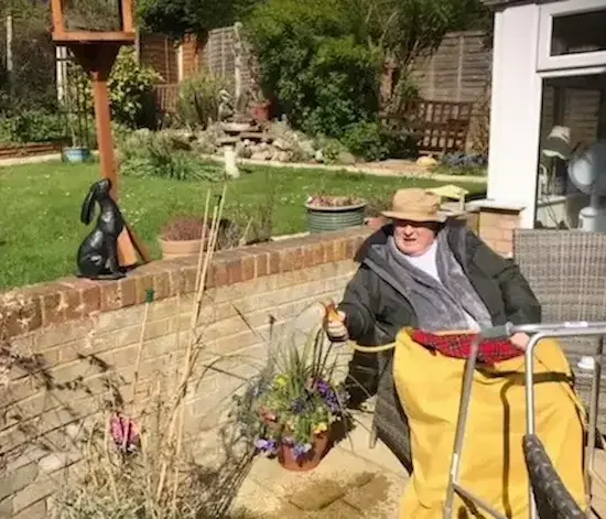 Domiciliary care client enjoying time outdoors Elderly client smiling in garden while seated with walking frame