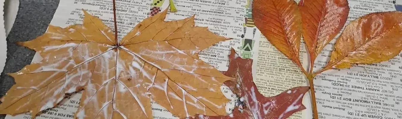 Autumn leaves painted and glued onto newspaper during a craft session